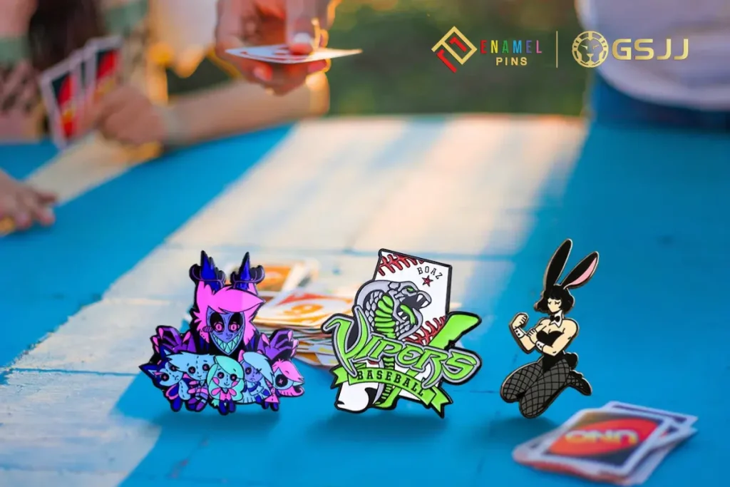 What Is MMR in Gaming and Why Does It Matter: Learn Here 2 Colorful custom enamel pins featuring cartoon characters and logos displayed on a blue table during a card game
